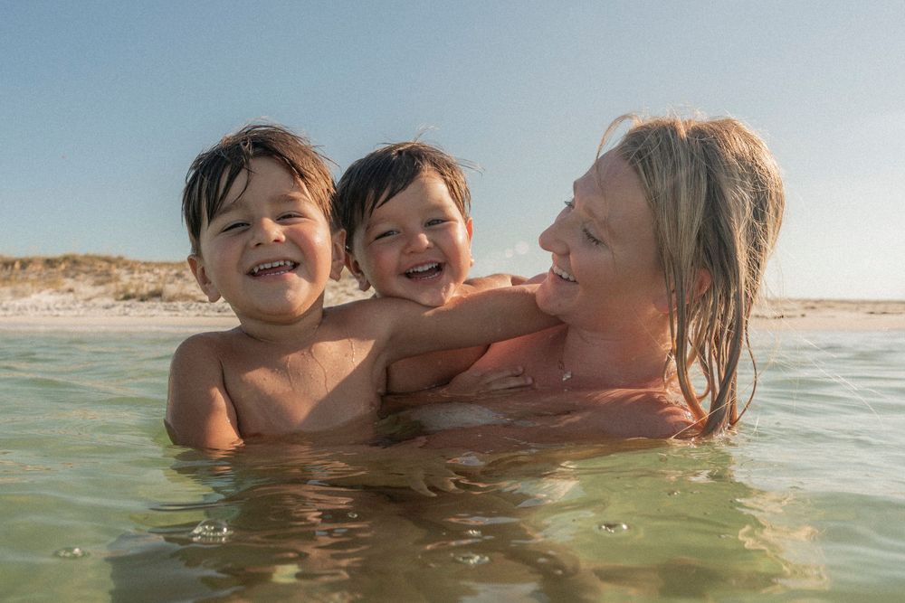 A joyful family enjoying an underwater photoshoot at the Destin Jetties, surrounded by clear emerald water and bright skies.