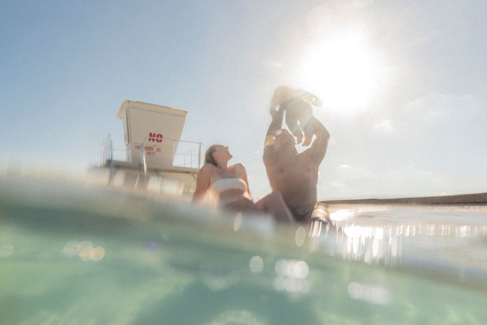 A joyful family enjoying an underwater photoshoot at the Destin Jetties, surrounded by clear emerald water and bright skies.
