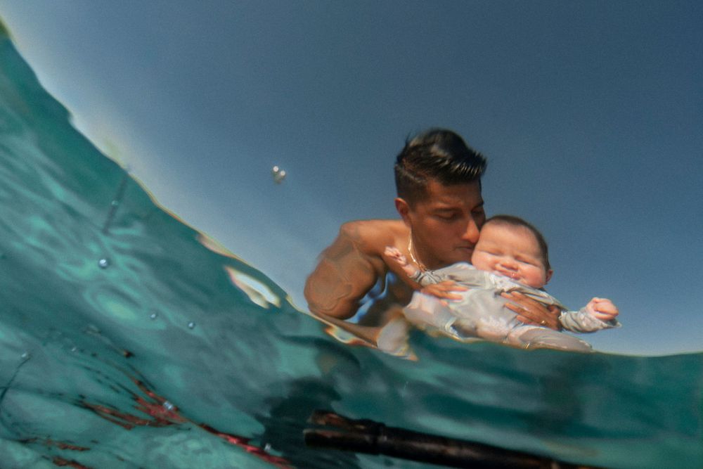 A joyful family enjoying an underwater photoshoot at the Destin Jetties, surrounded by clear emerald water and bright skies.