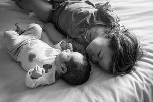 Black and white image of intimate family moment while resting together on bed.