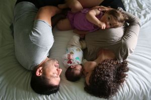Family members lying close together on bed sharing tender moment from above perspective.