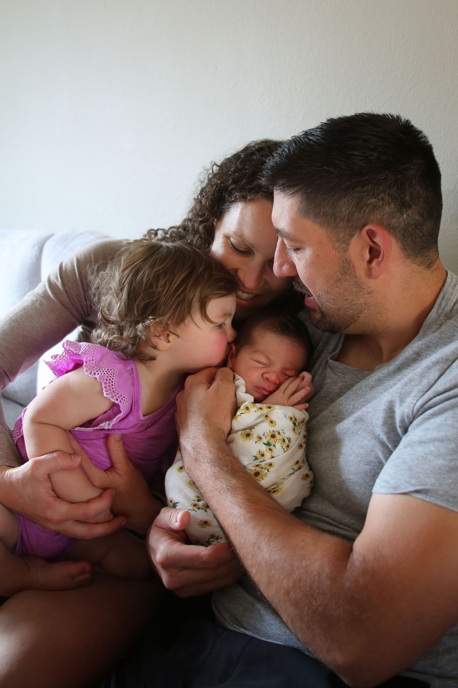 Family members share an intimate moment with a newborn baby in a cozy setting.