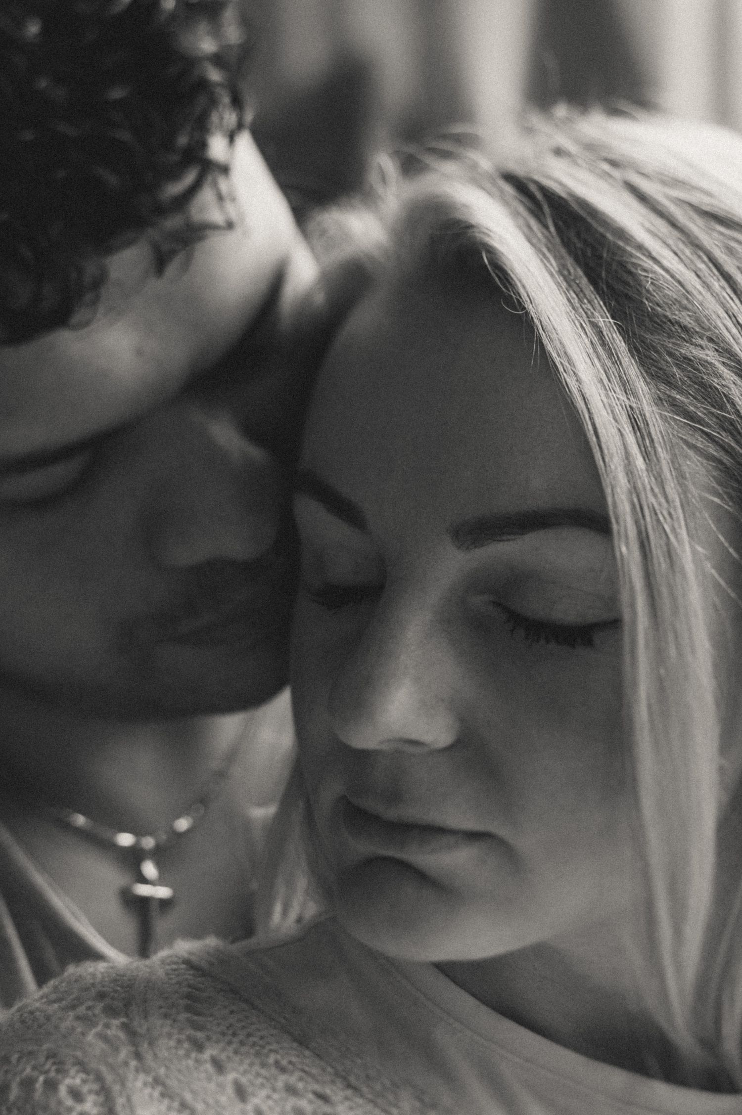Intimate black and white close-up portrait showing tender moment between couple.