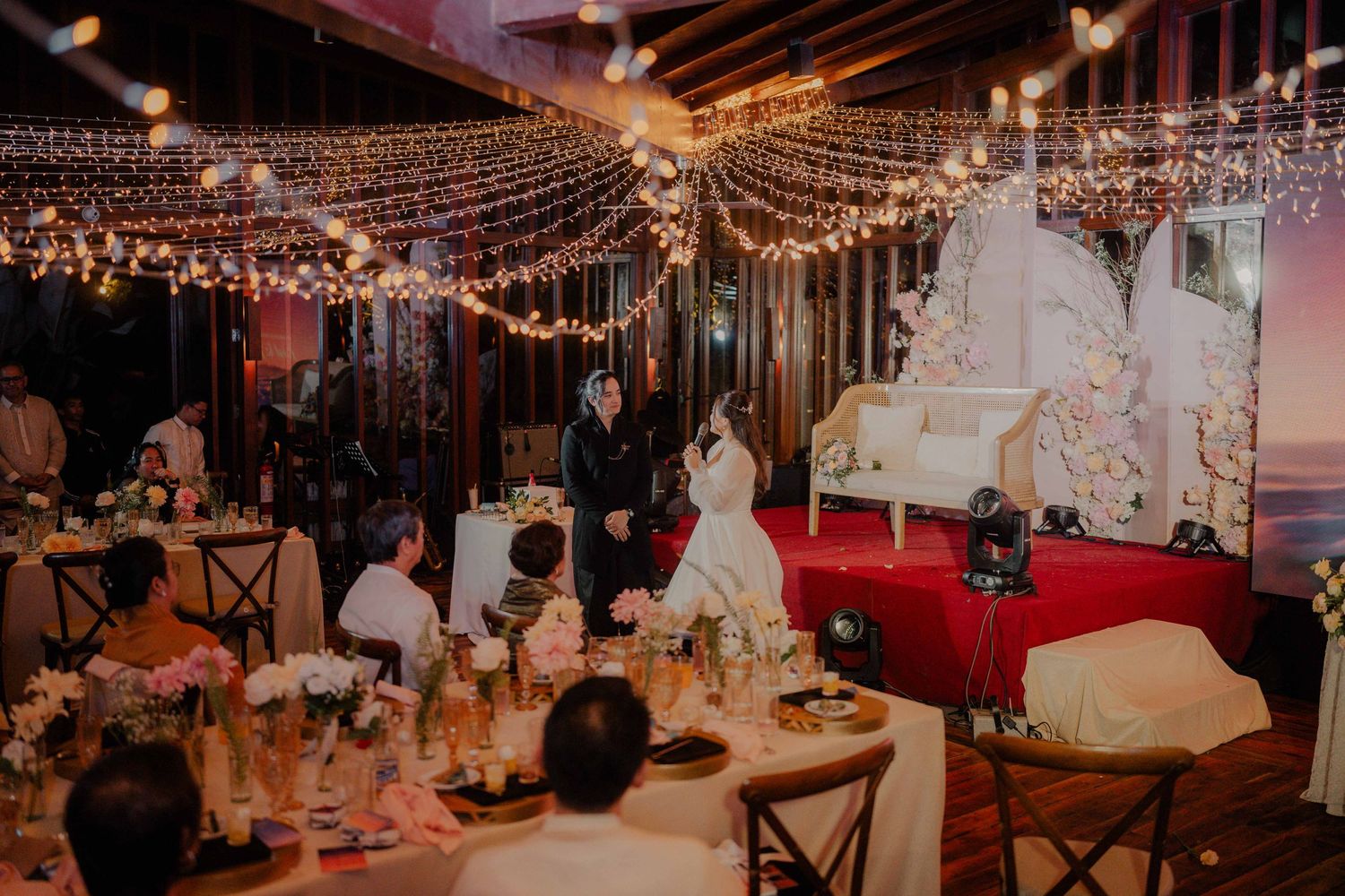 Wedding reception venue decorated with twinkling string lights and elegant table settings.