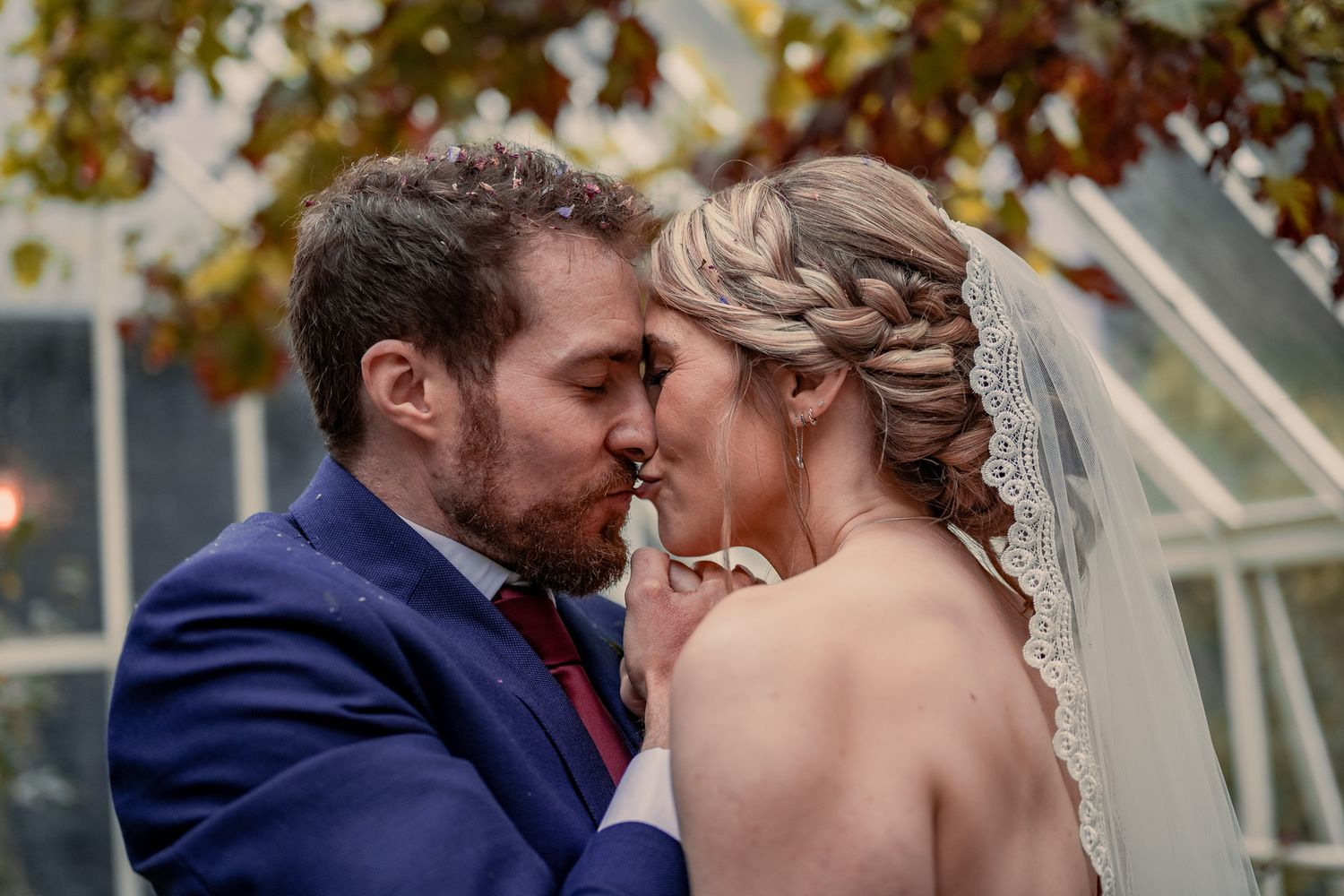 Happy newlyweds share an intimate moment outdoors with bride in strapless dress and groom in navy suit.
