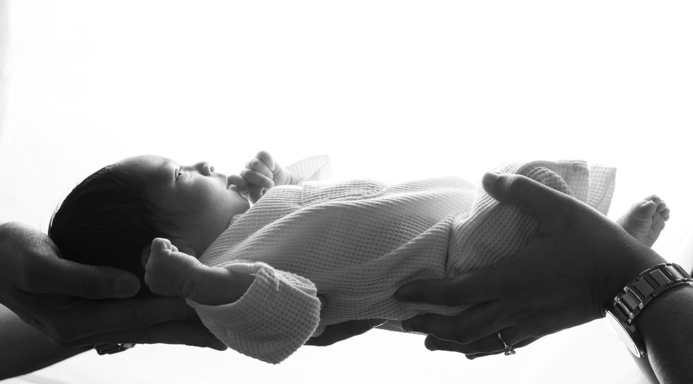Black and white profile view of infant sleeping peacefully in soft clothing.