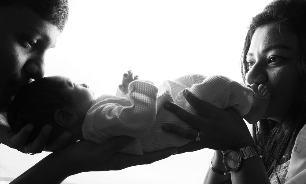 A black and white photograph showing three people gathered closely together in an intimate moment.