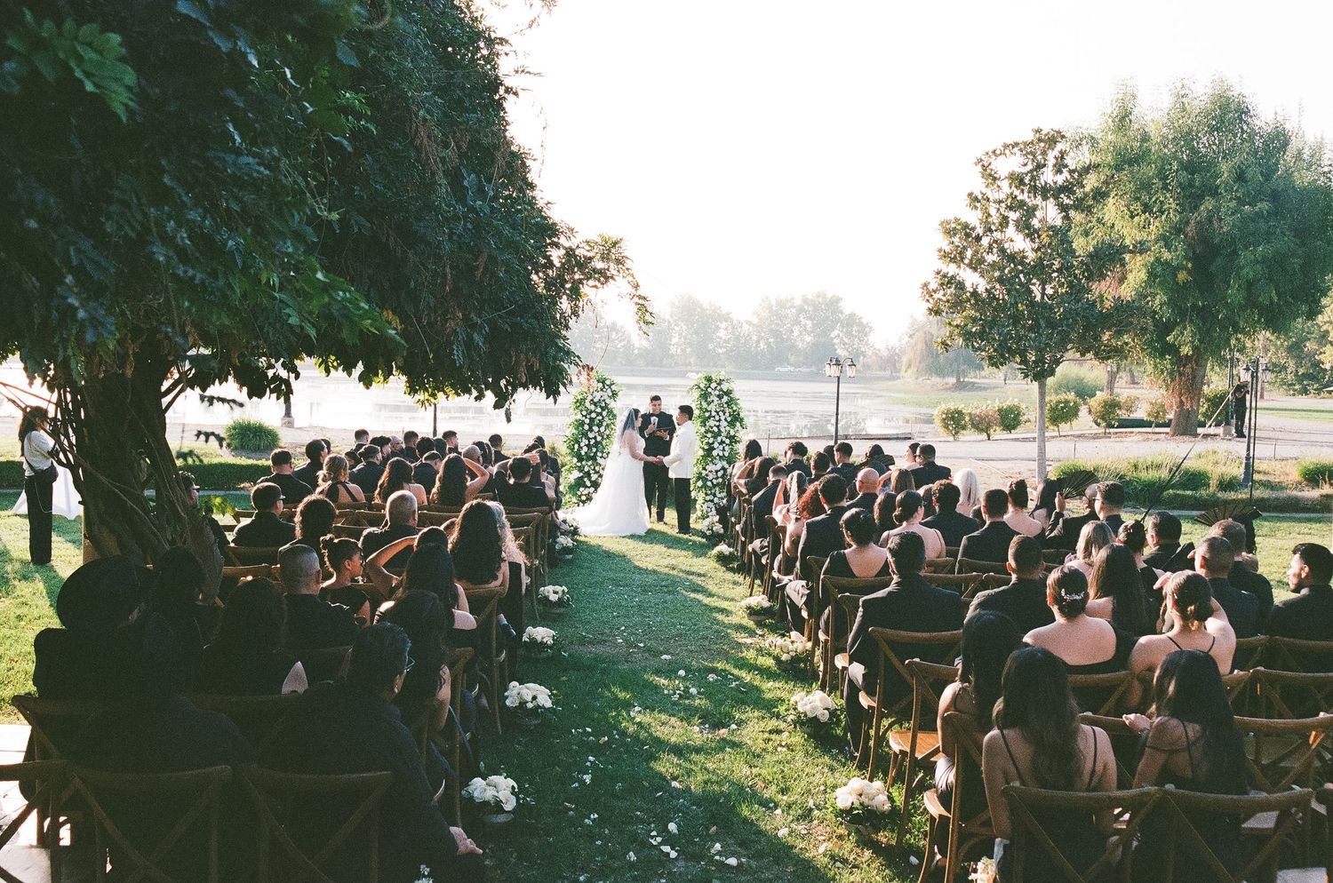 Outdoor forest wedding ceremony with string lights and guests seated on wooden chairs. Kentucky. Cave wedding. Documentary photographer