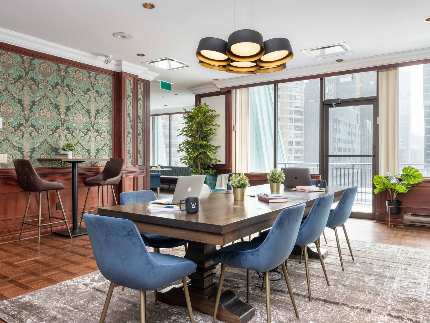 Elegant conference room with blue velvet chairs, patterned wallpaper, and modern lighting fixtures.