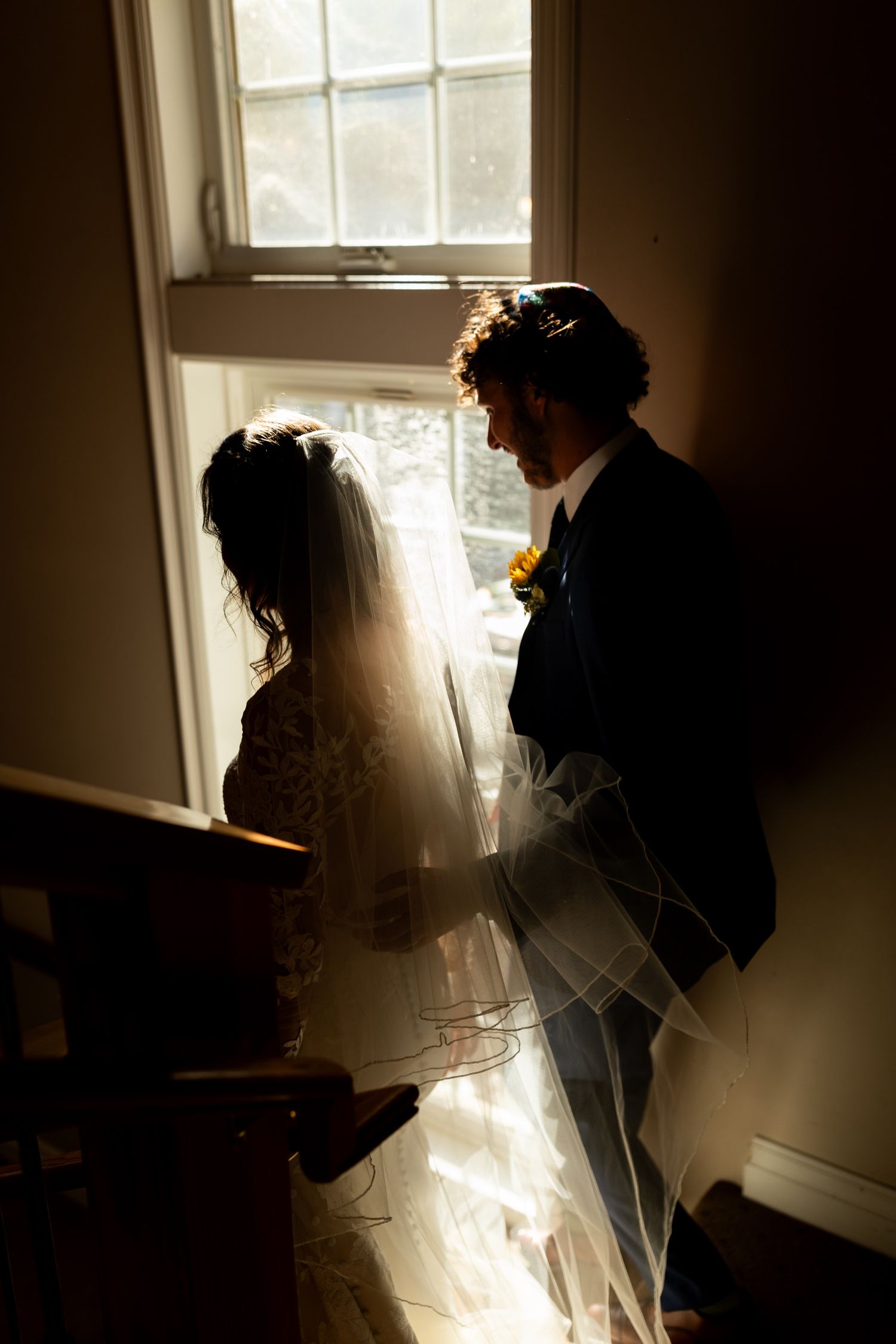 Silhouetted figures walking down a staircase in dramatic window lighting creating moody atmosphere.