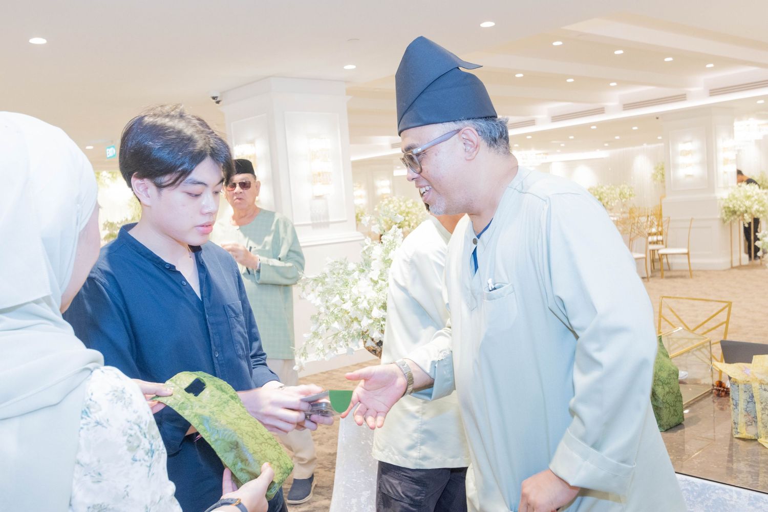People in business attire exchange items at an indoor venue.