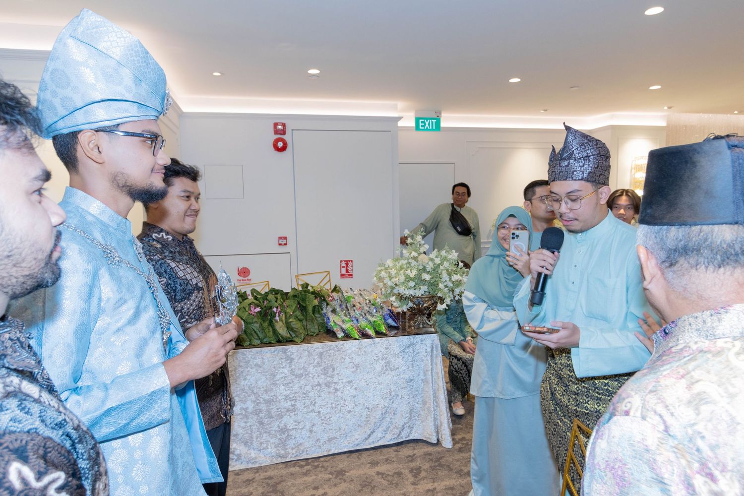 Group gathering in light blue traditional formal wear during an indoor celebration event.