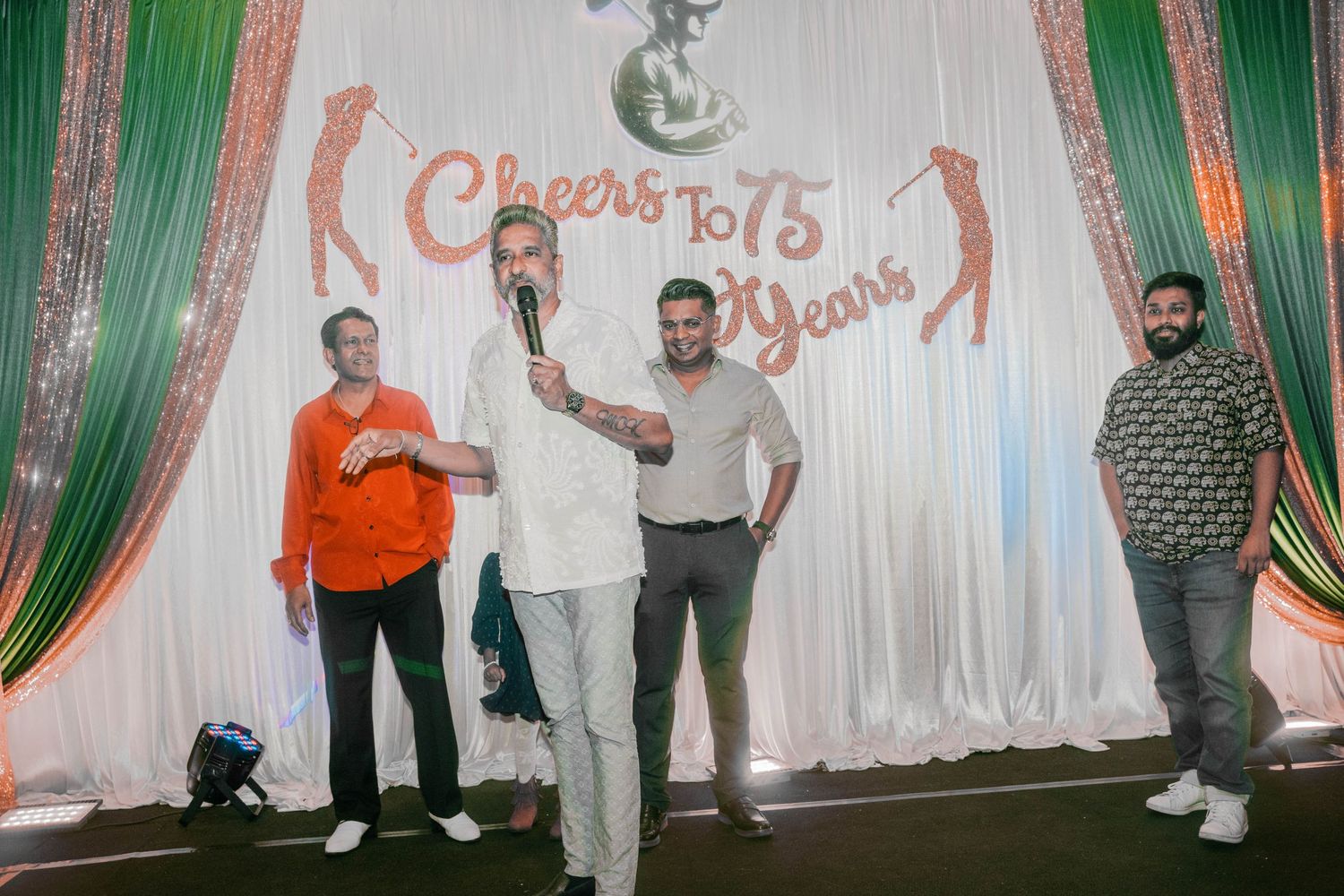 People celebrating in front of a decorative backdrop with text reading 'Cheers to 15 Years'.
