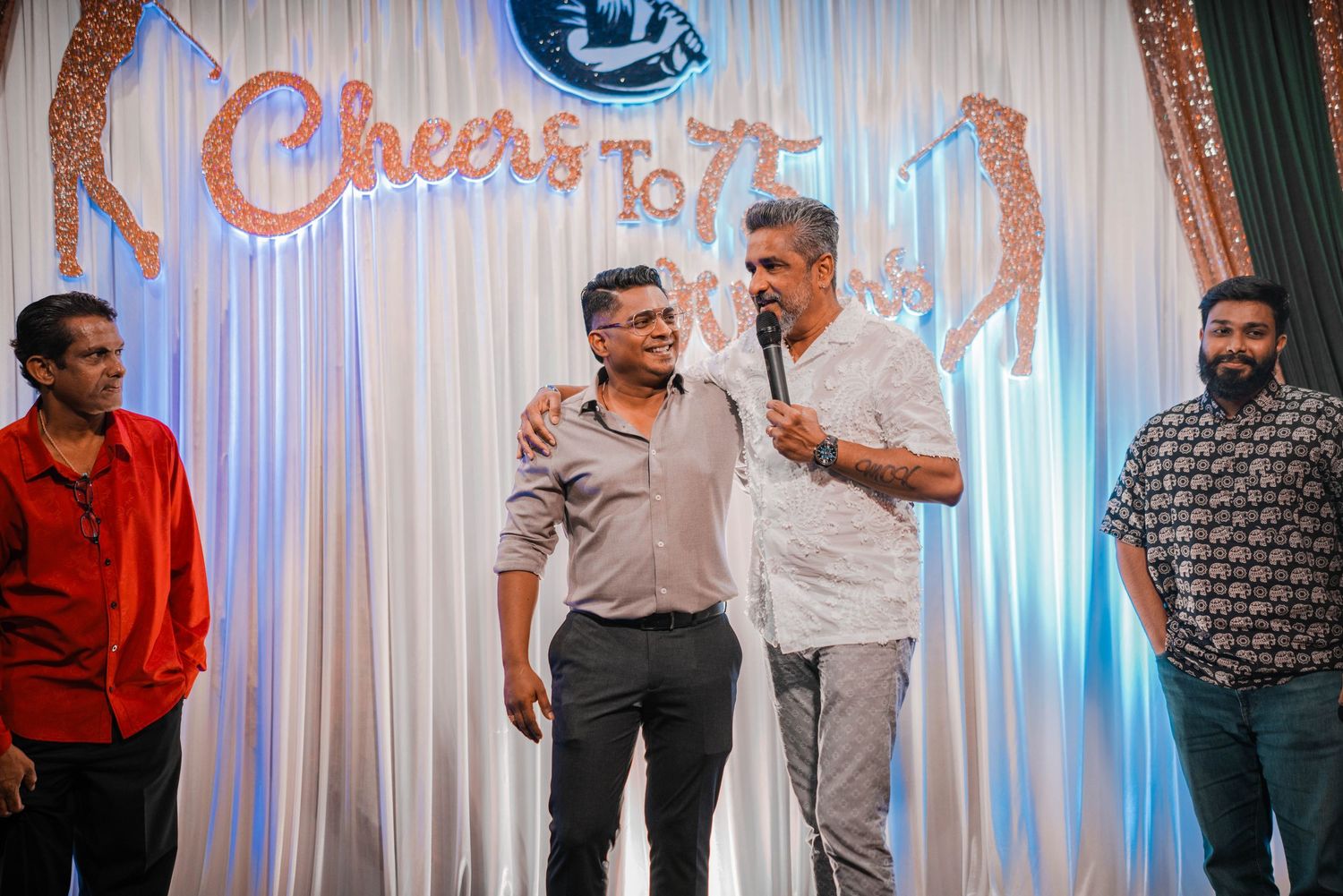 People gathered in front of a celebratory backdrop during what appears to be an anniversary event.
