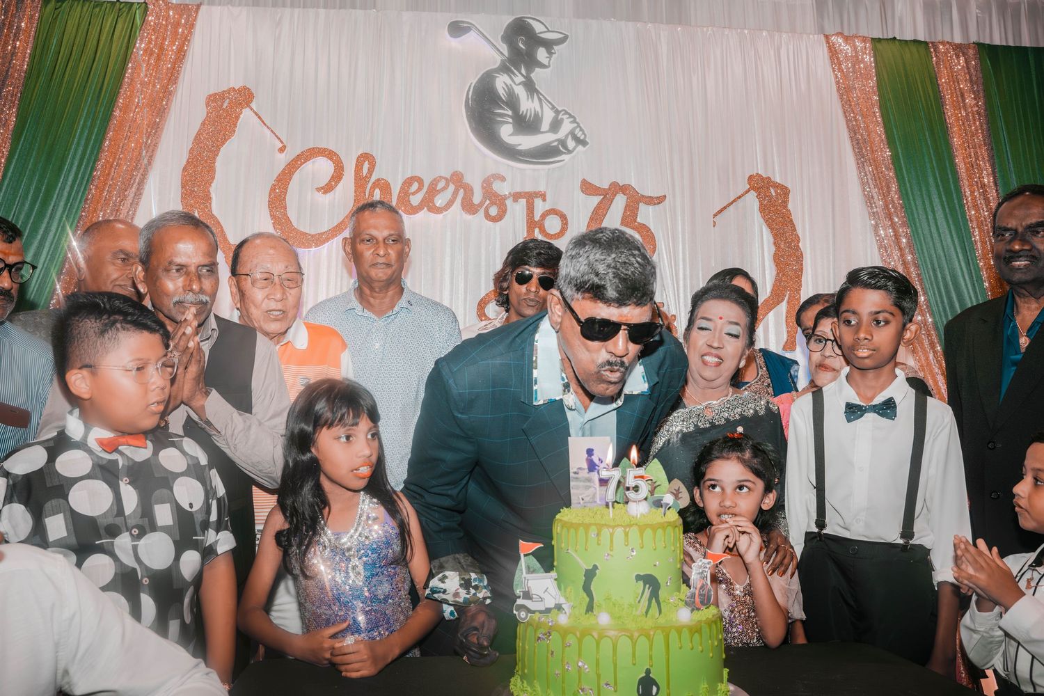 Group photo of celebrants gathered around a cake at what appears to be a 15th anniversary celebration.