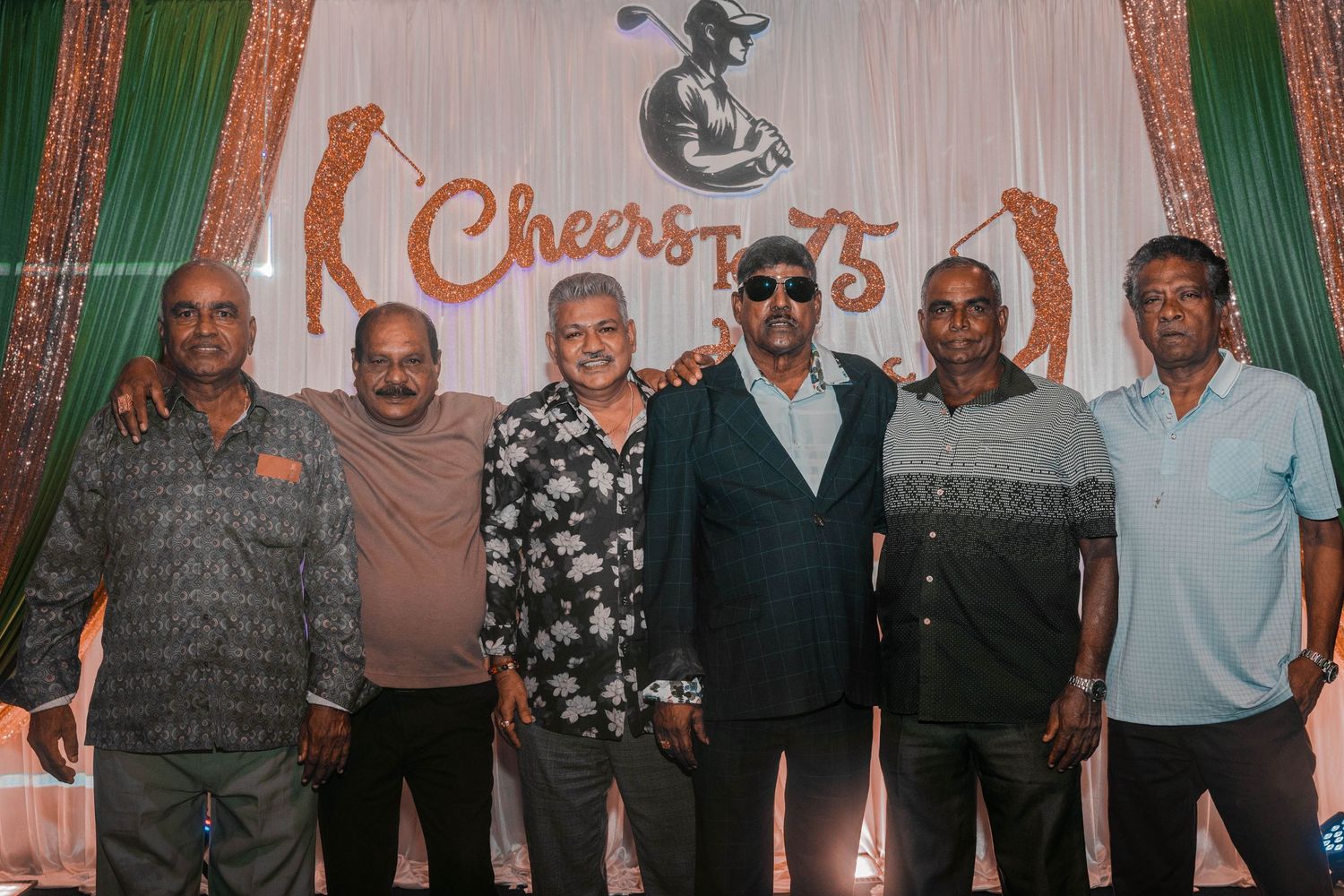 Group photo of attendees at a 75th anniversary celebration with branded backdrop and lighting.