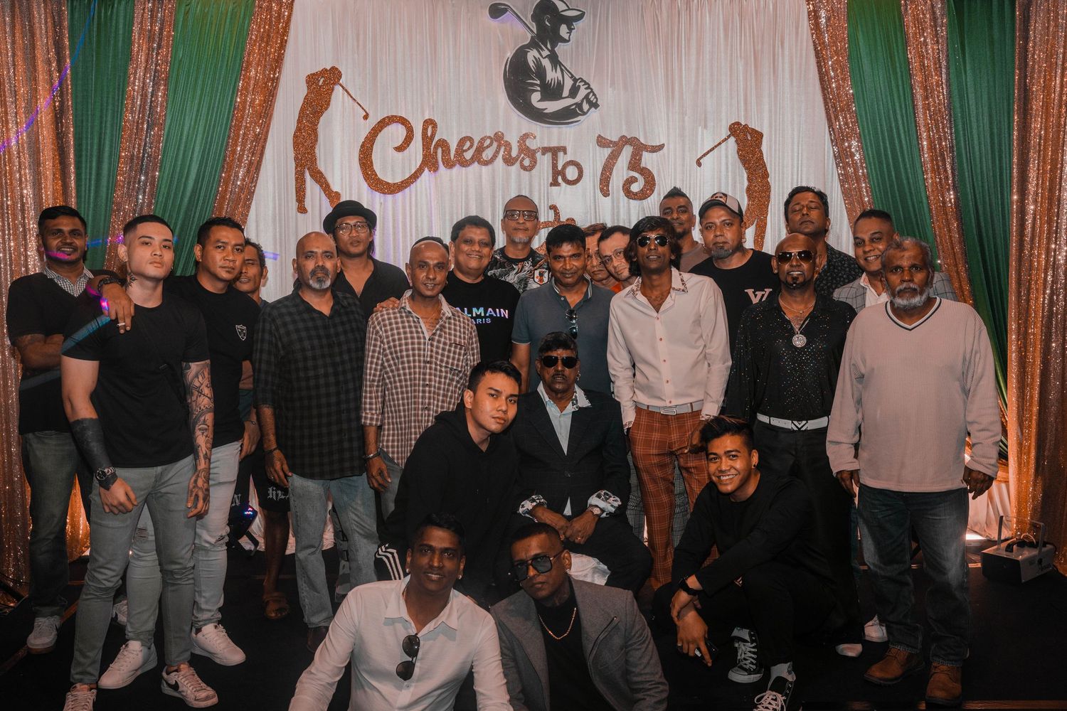 Large group photo of celebration attendees gathered in front of a branded backdrop at an anniversary event.