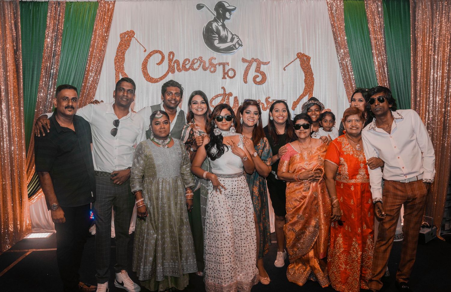 Diverse group of attendees posing together at a formal celebration event with decorated backdrop.
