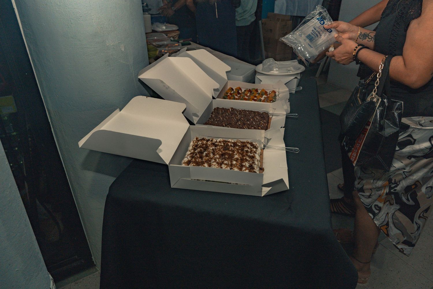 Several boxes of food items are displayed on a dark table at an event.