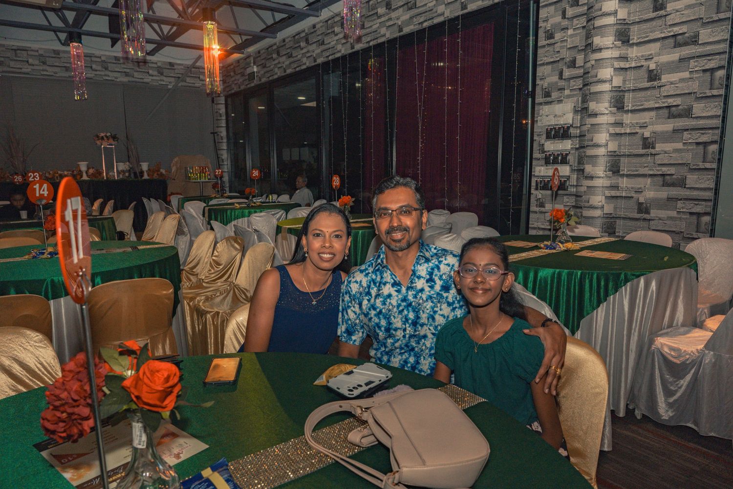 Guests seated at decorated tables during an evening celebration with orange and green decor.