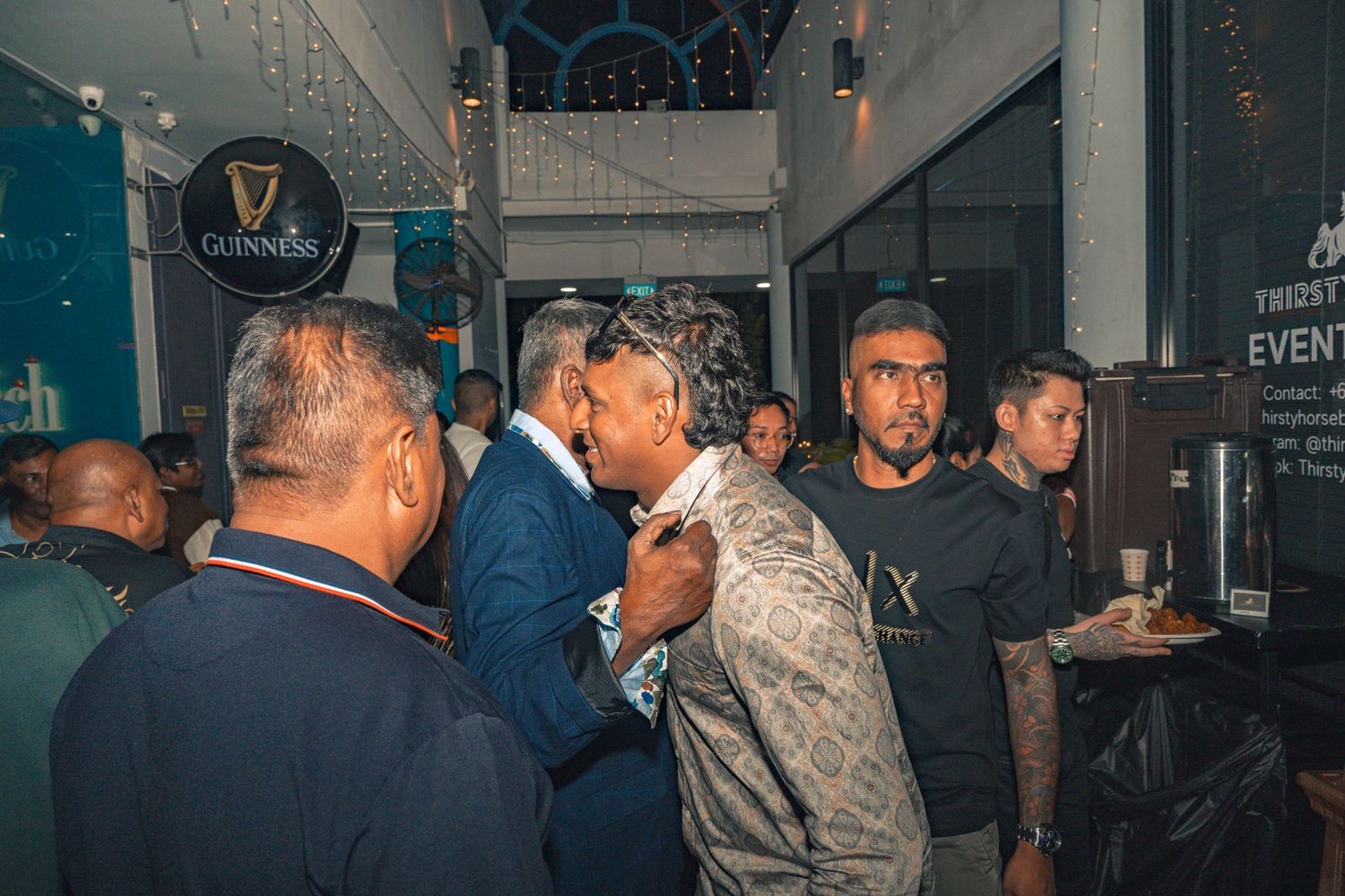 People socializing in a dimly lit bar or nightclub setting with illuminated signs.