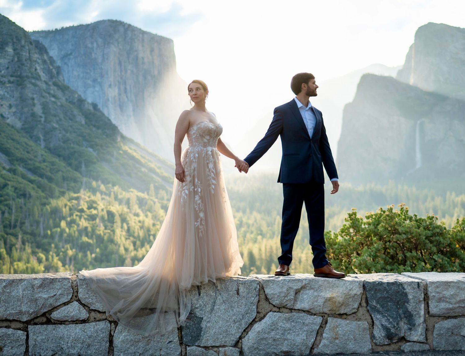 An elegant bride and groom hold hands in a soft sunrise at Tunnelview, Yosemite, Cailfornia