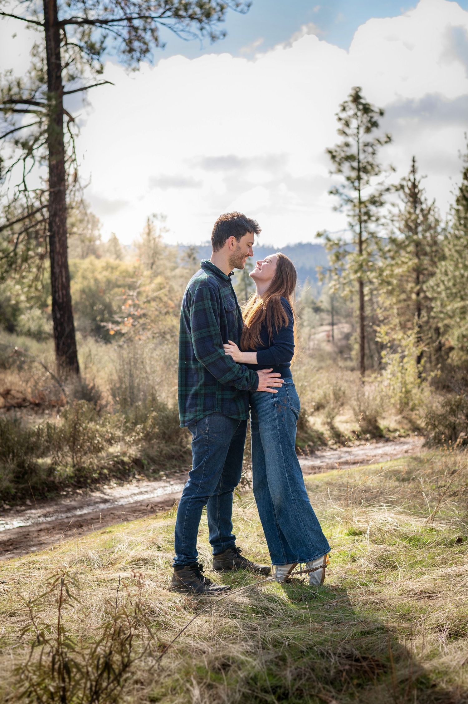 A lady reaches up to kiss her man in the forested mountainous foothills of Greeley Hill, California