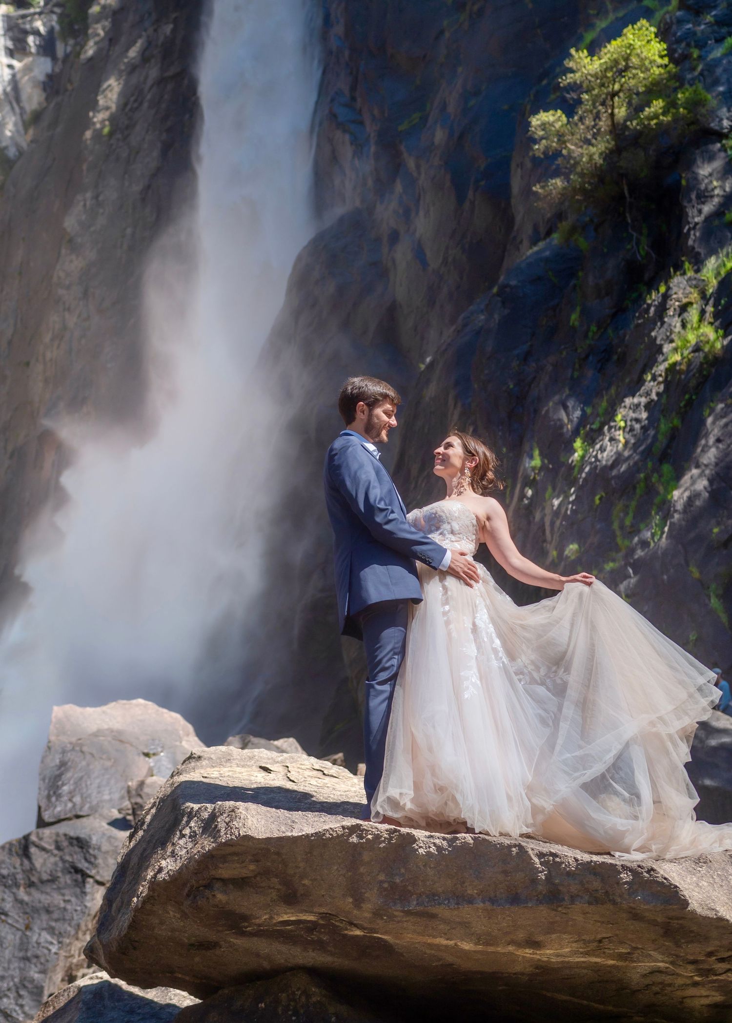 A bride and groom embrace in front of a waterfall, Yosemite Falls