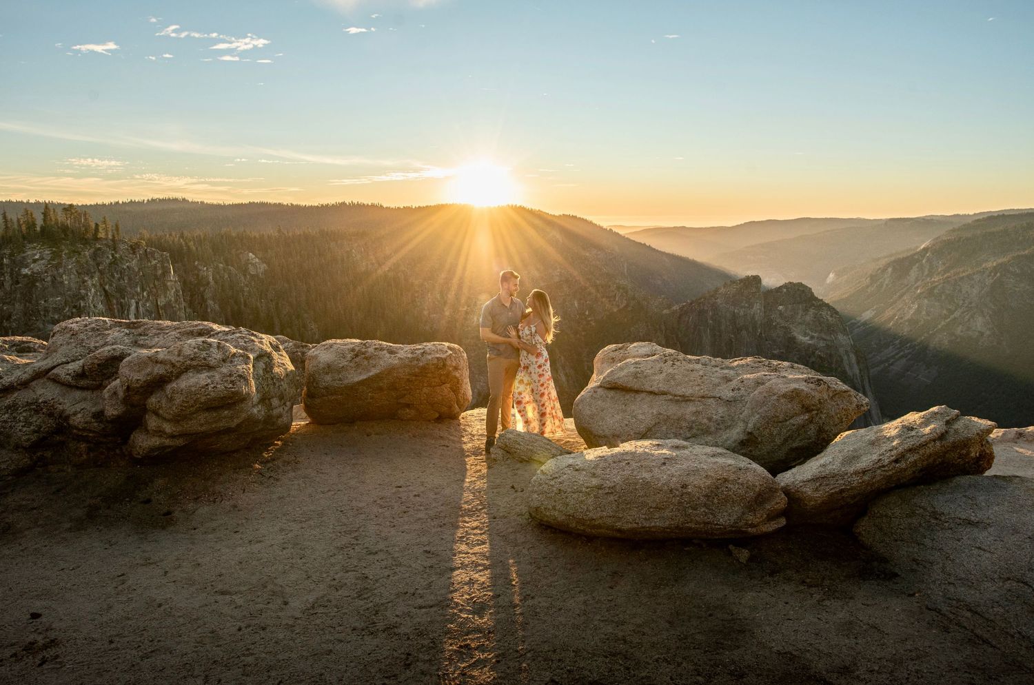 An embracing newly engaged couple on Taft Point Yosemite during golden sunset hour