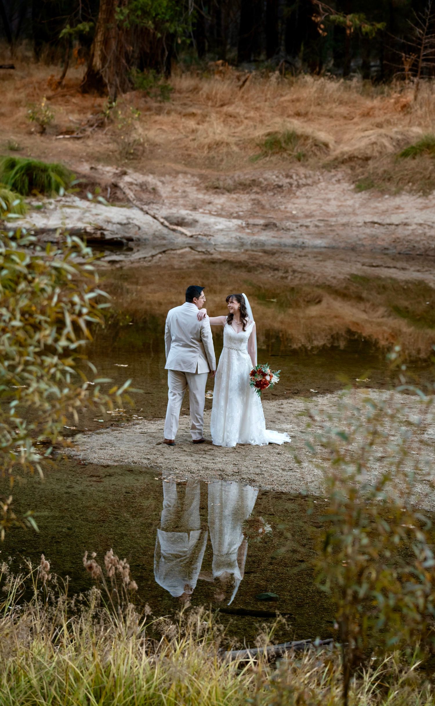 A bride and groom reflection on the river, Yosemite, California