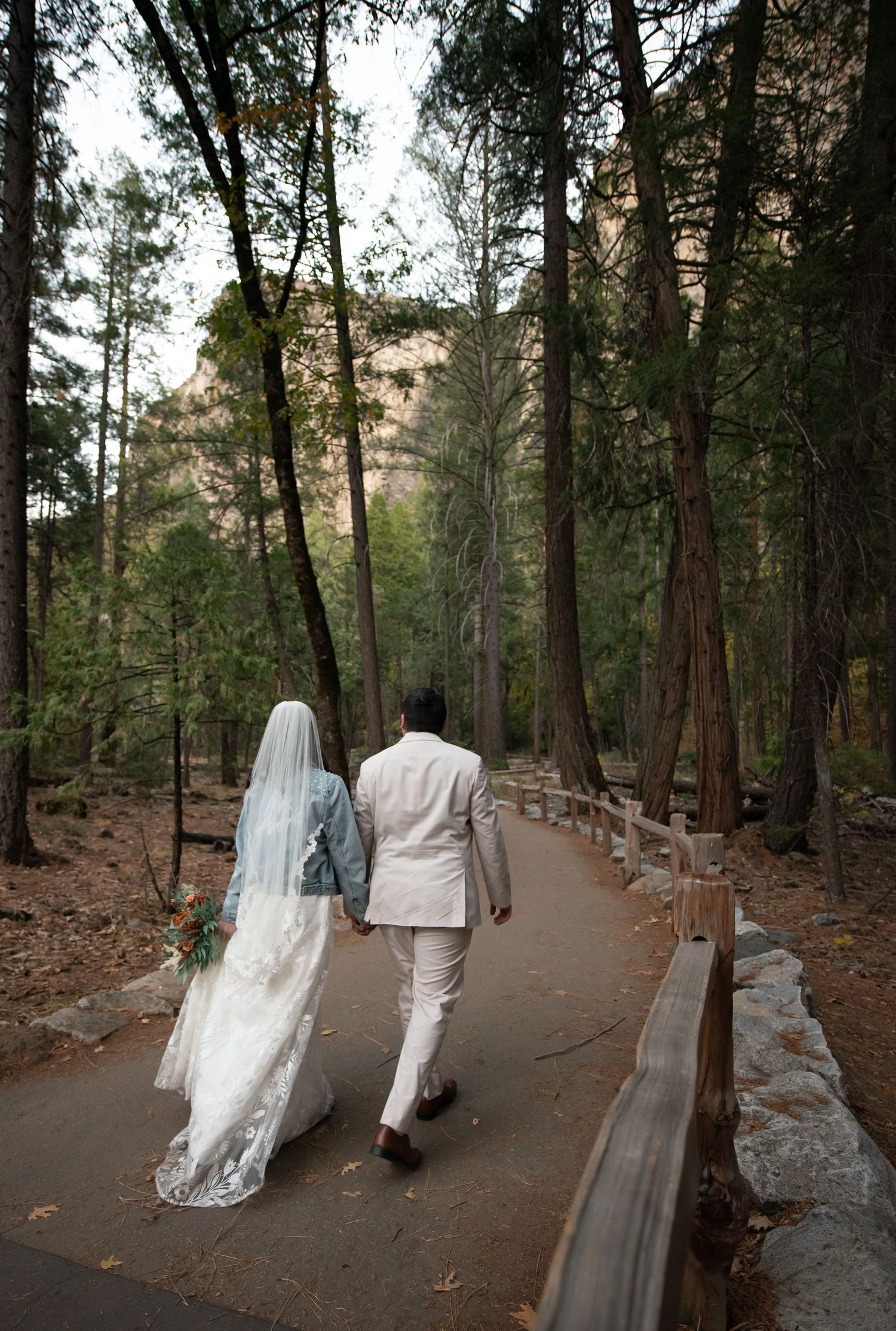 A bride and groom walk together toward Bridal Veil Falls, Yosemite