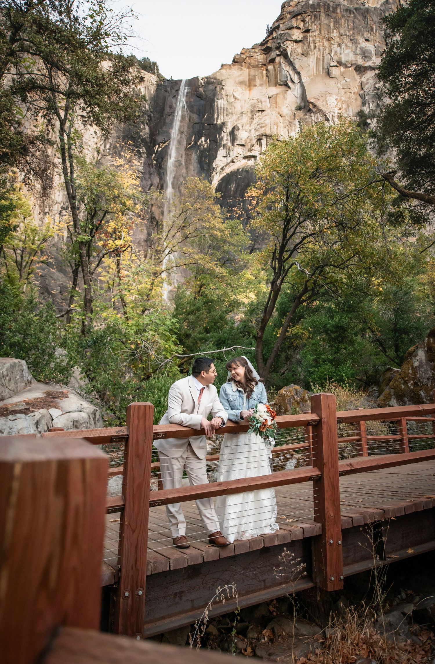 A bride and groom kiss in front of Bridal Veil Falls, Yosemite