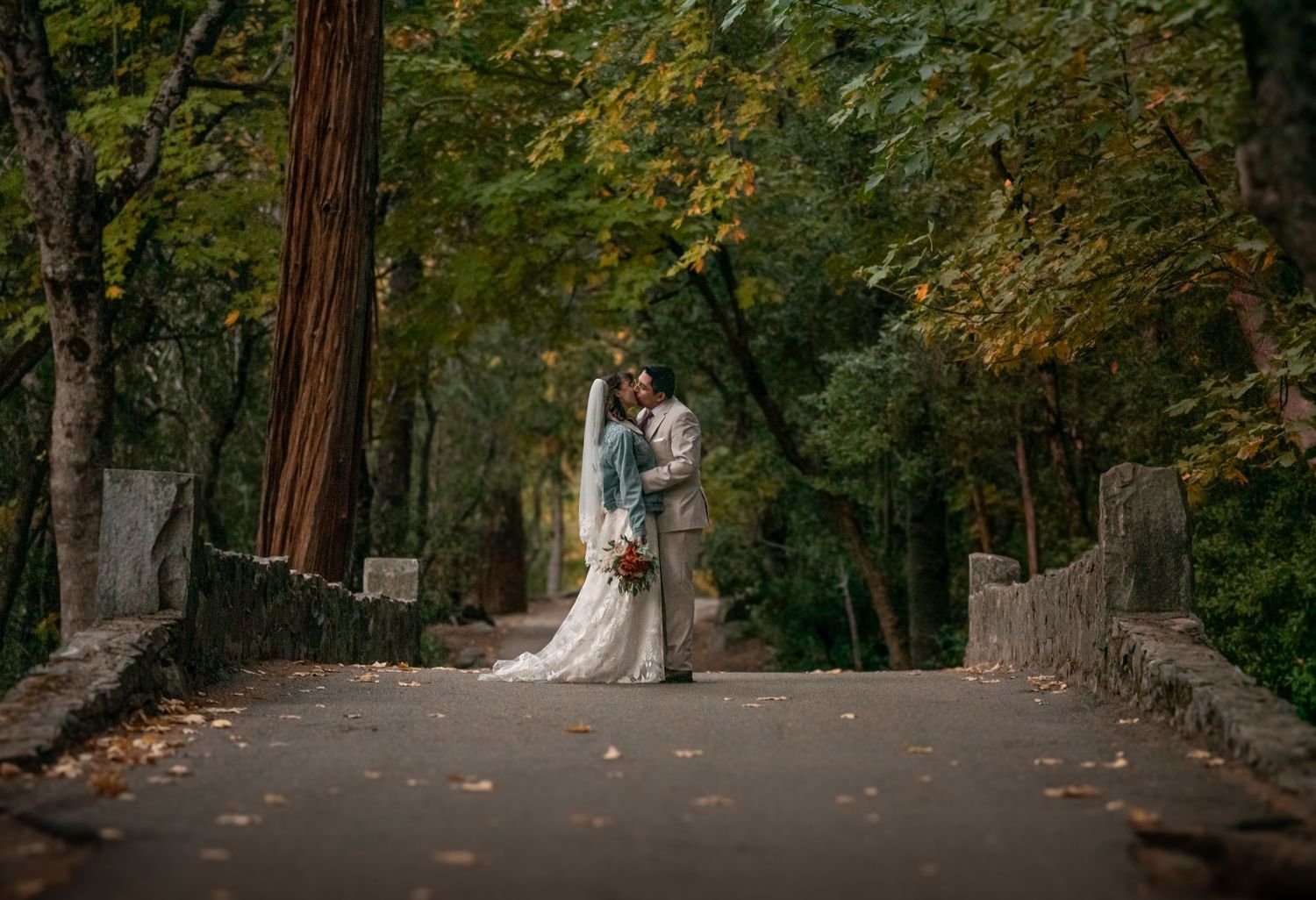 A bride and groom dancing on a bridge in Yosemite