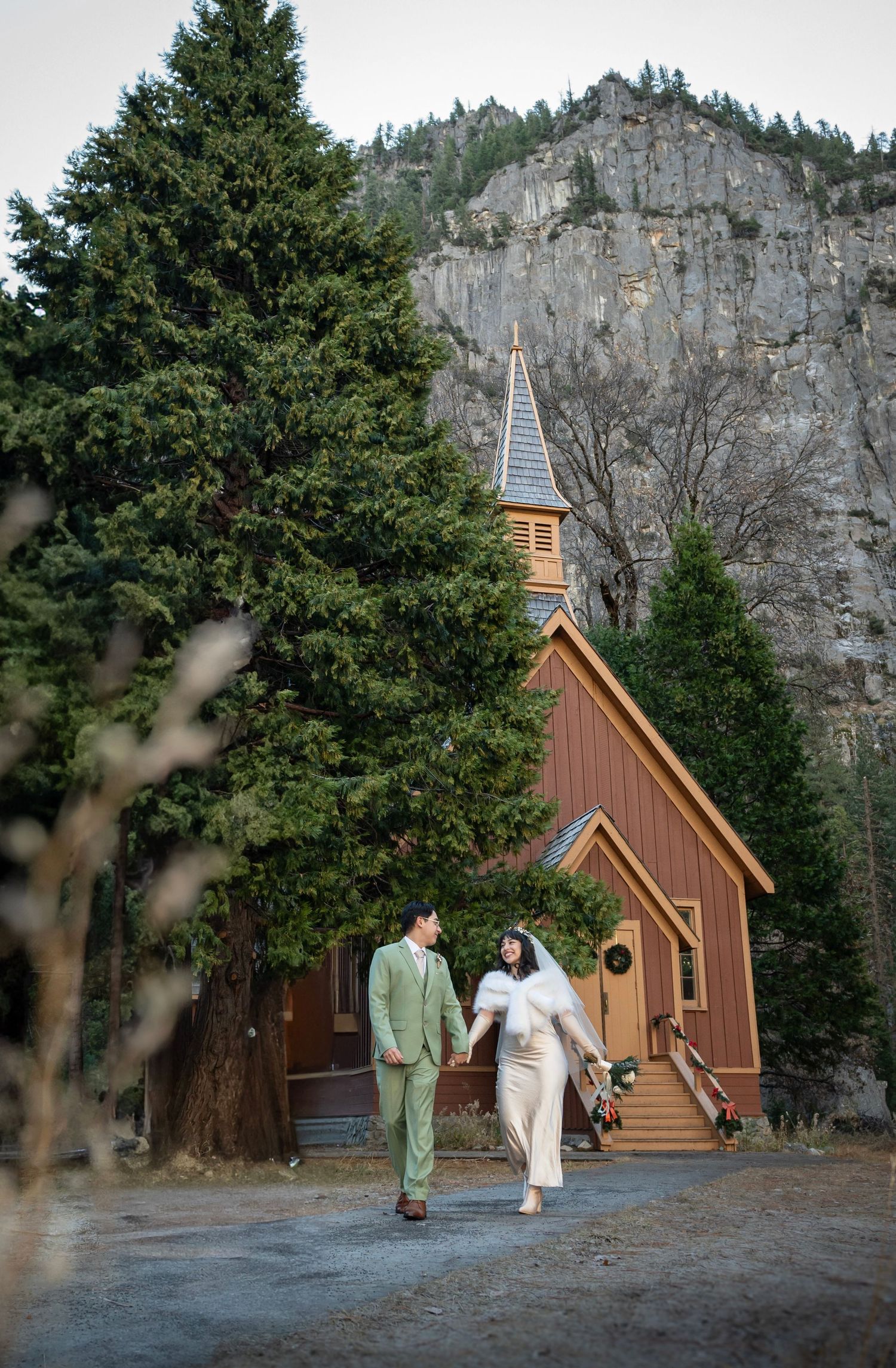 A bride and groom elopement running together in front of Yosemite Chapel