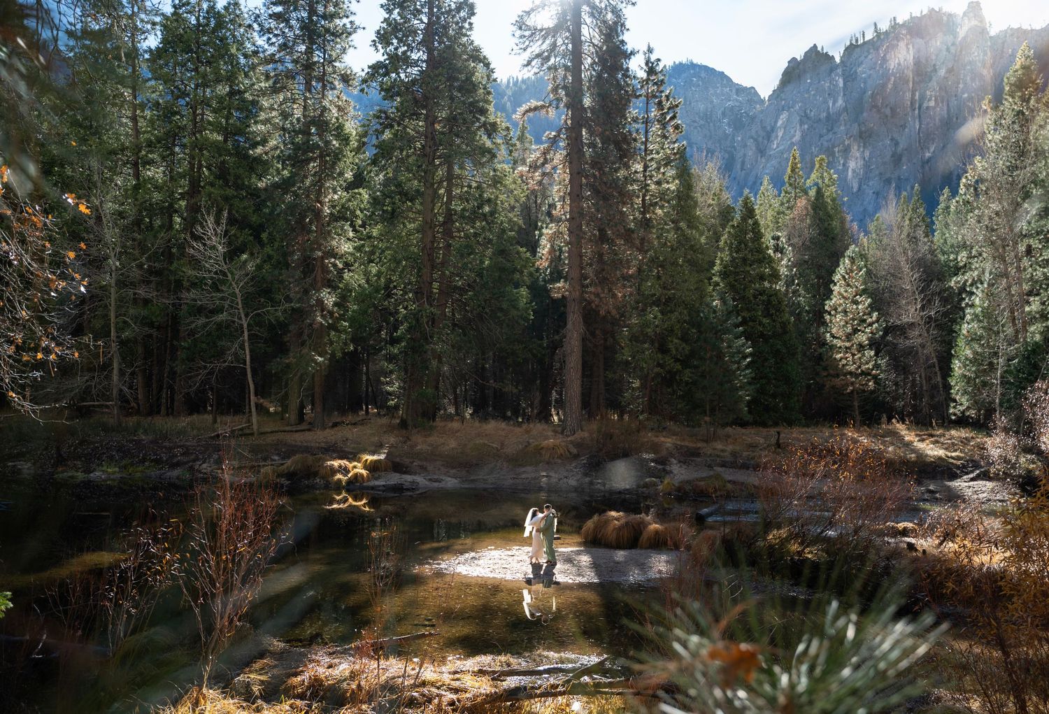 A bride and groom dancing on a sandbar at the river in Yosemite