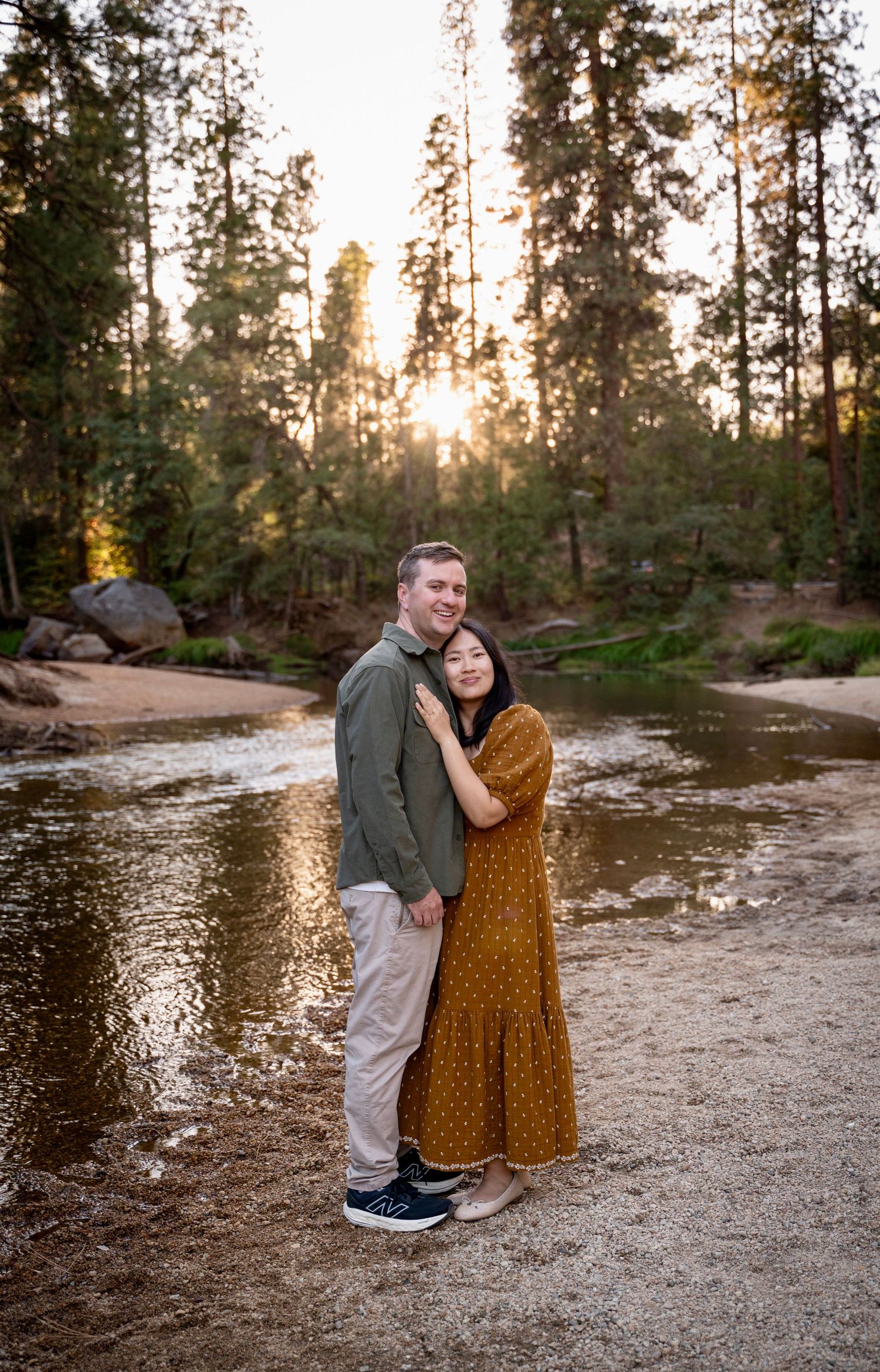 A couple hug with soft backlit sunset on a beach by the river in Yosemite Valley