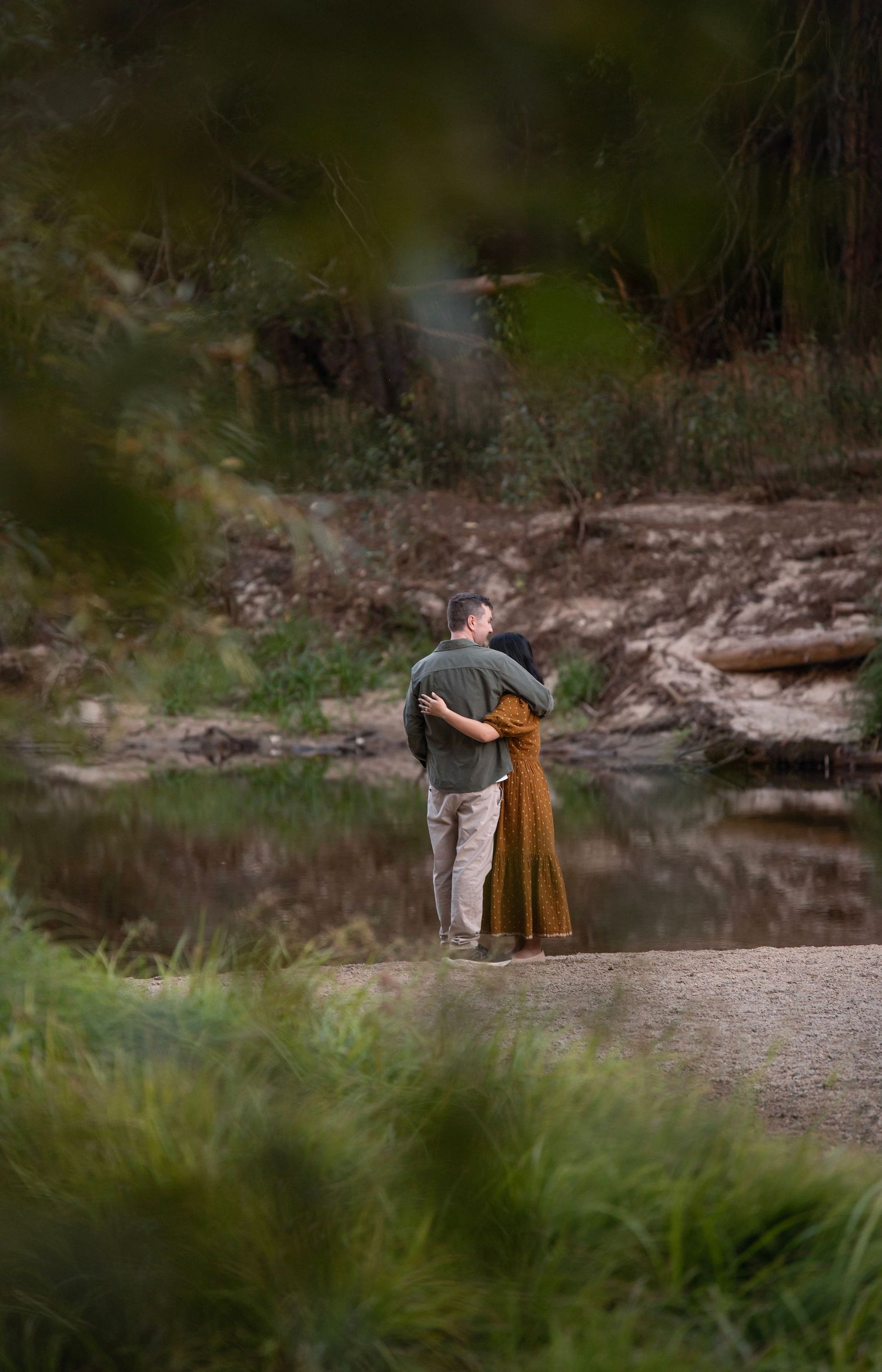 a newly engaged couple hug by the river in Yosemite, California