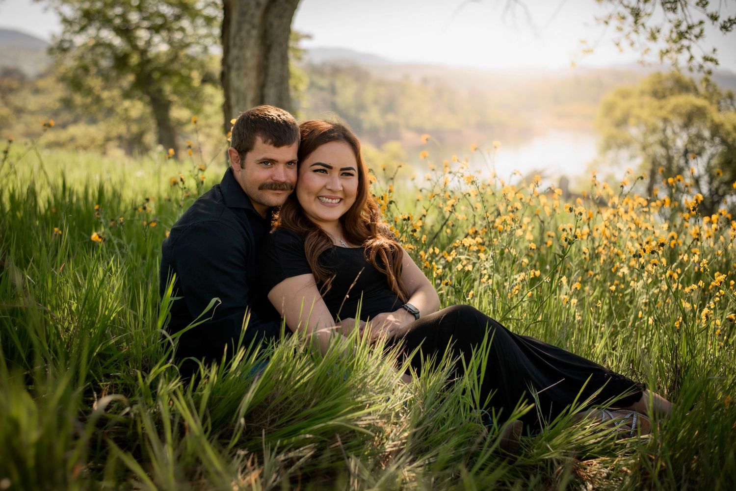 A couple lay together in golden yellow orange wildflowers in spring