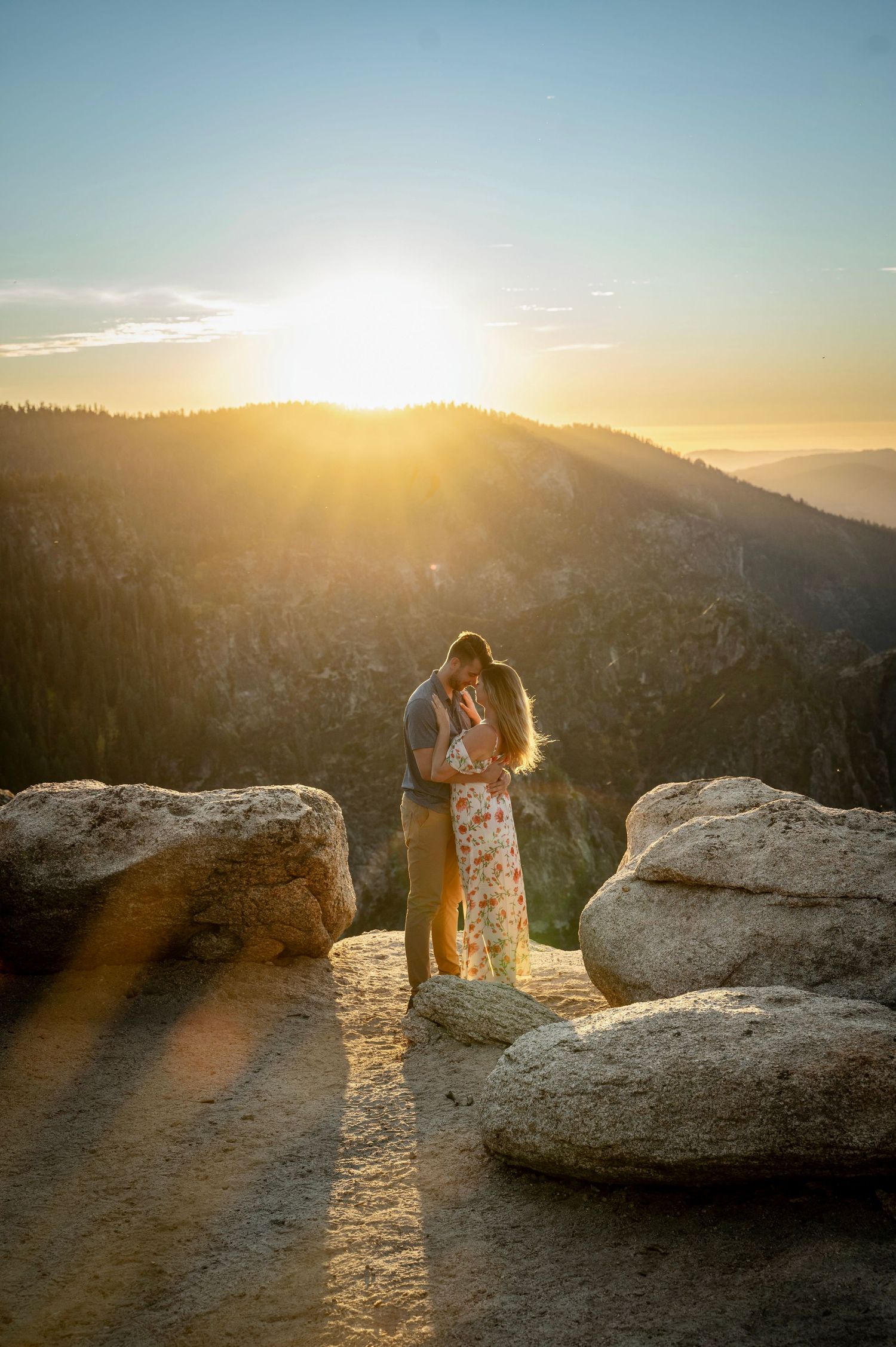 An embracing newly engaged couple on Taft Point Yosemite during golden sunset hour