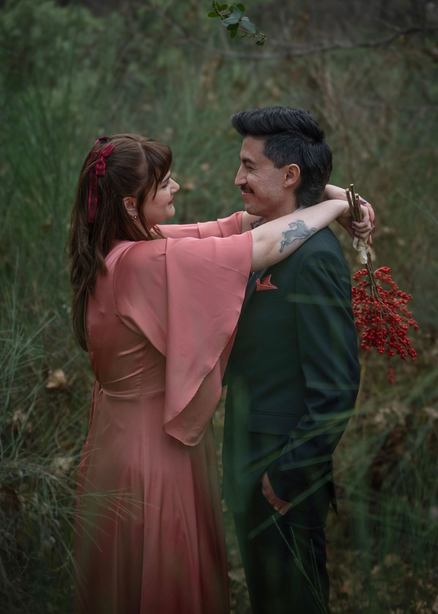 A bride and groom embrace in a soft green forest
