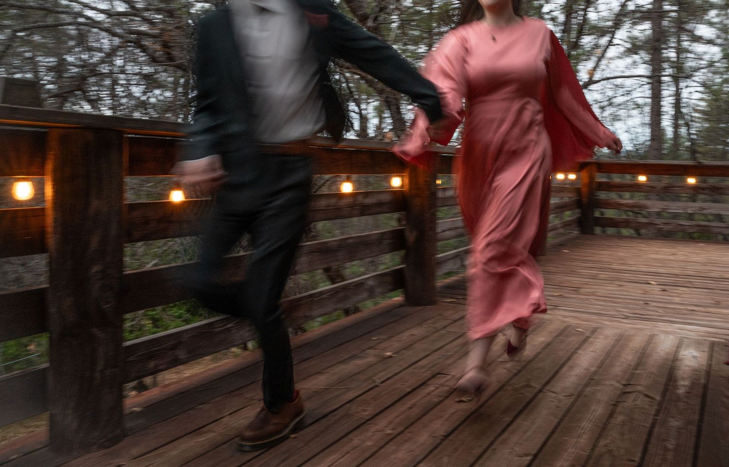 A bride and groom run in a blurred photo with string lights
