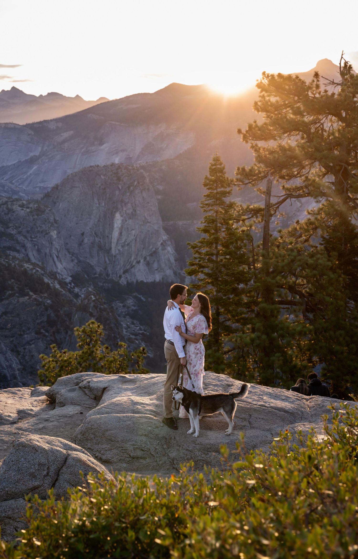 a beautiful engaged couple with their dog in Yosemite as a backdrop, at Glacier Point and Half Dome in the background, at sunrise