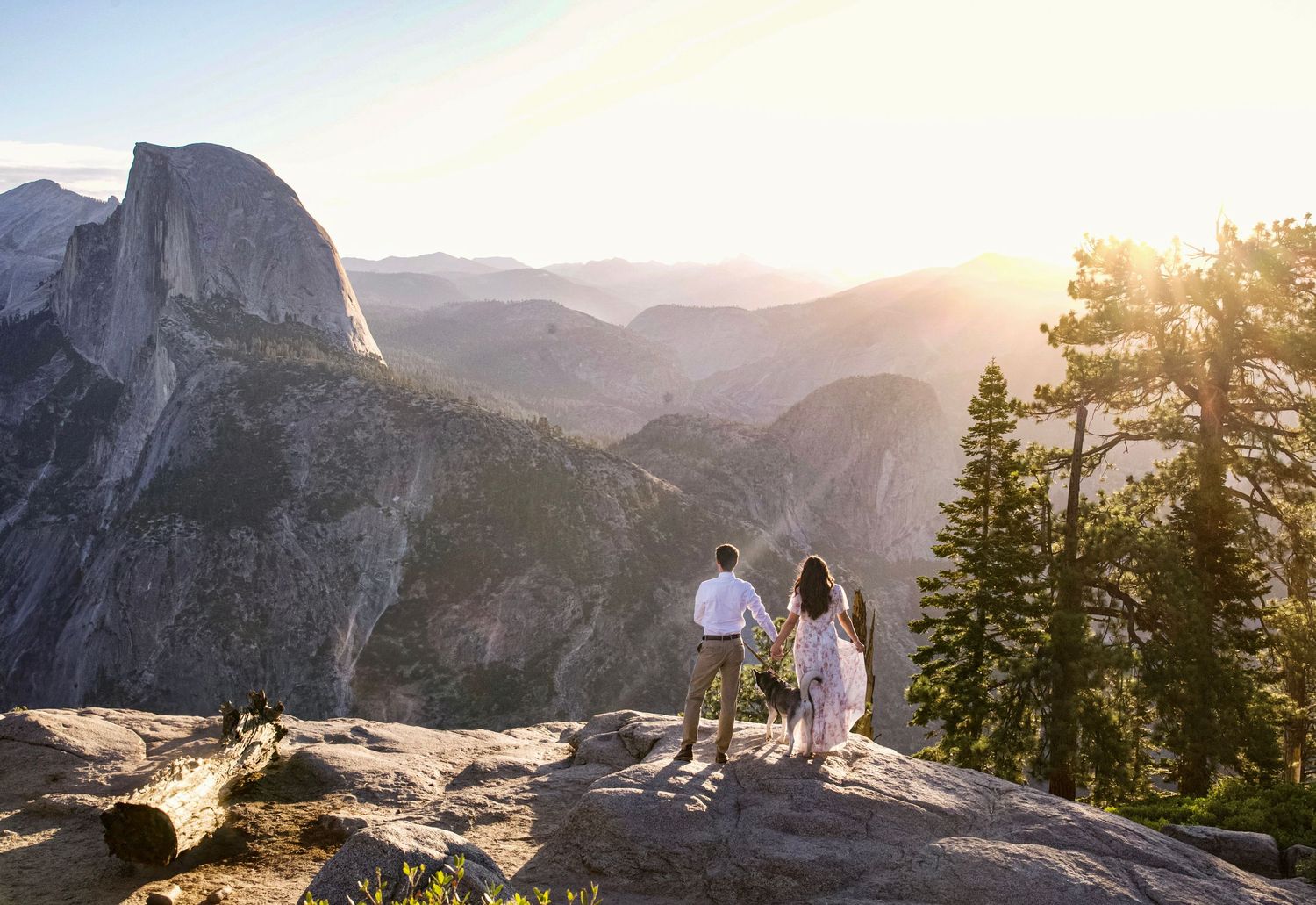a beautiful engaged couple with their dog in Yosemite as a backdrop, at Glacier Point and Half Dome in the background, at sunrise