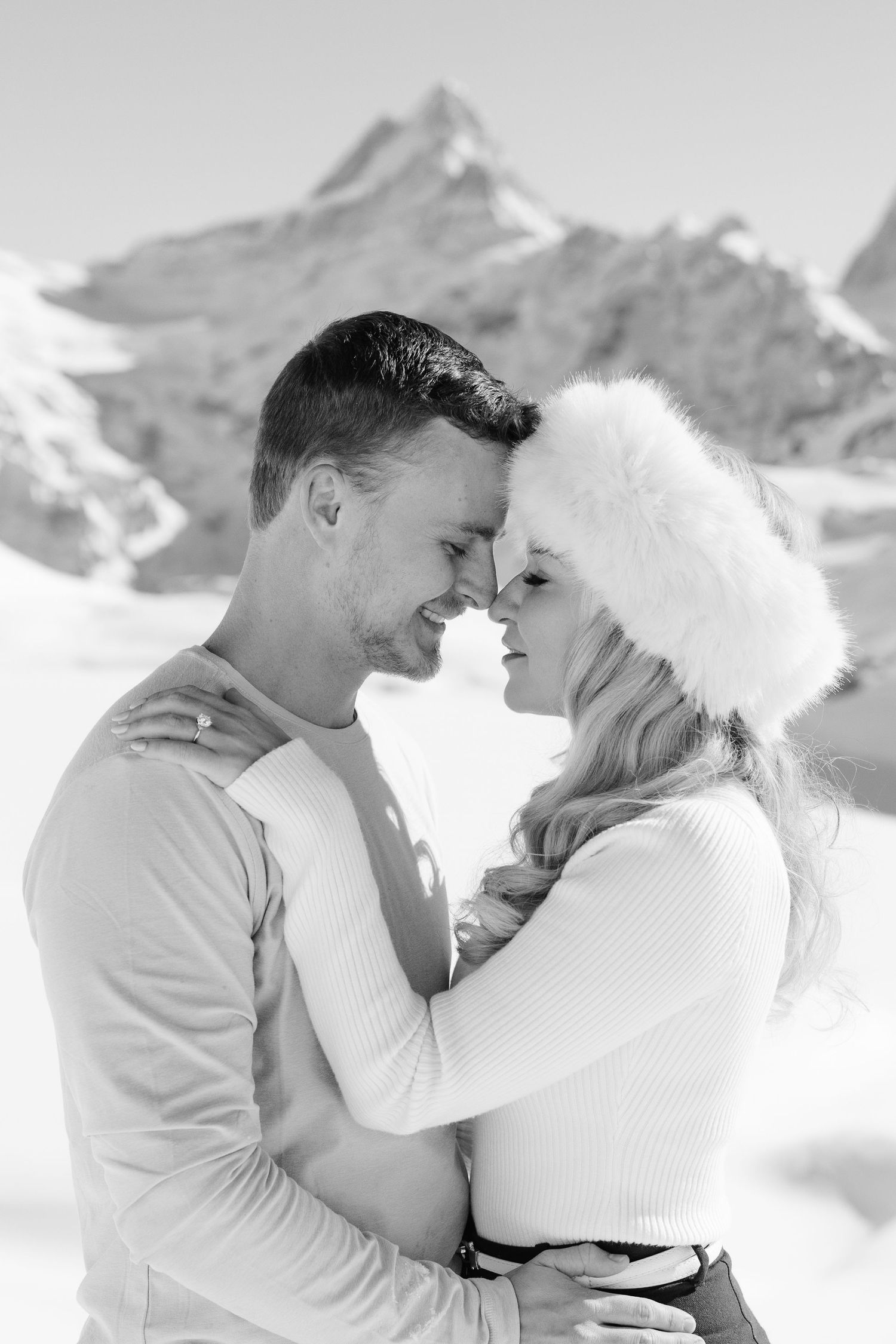 A candid black and white photo of a couple laughing together in nature, above Lauterbrunnen, Switzerland.