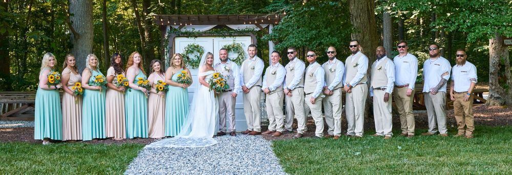 Wedding party in pastel attire poses outdoors with bridesmaids and groomsmen.
