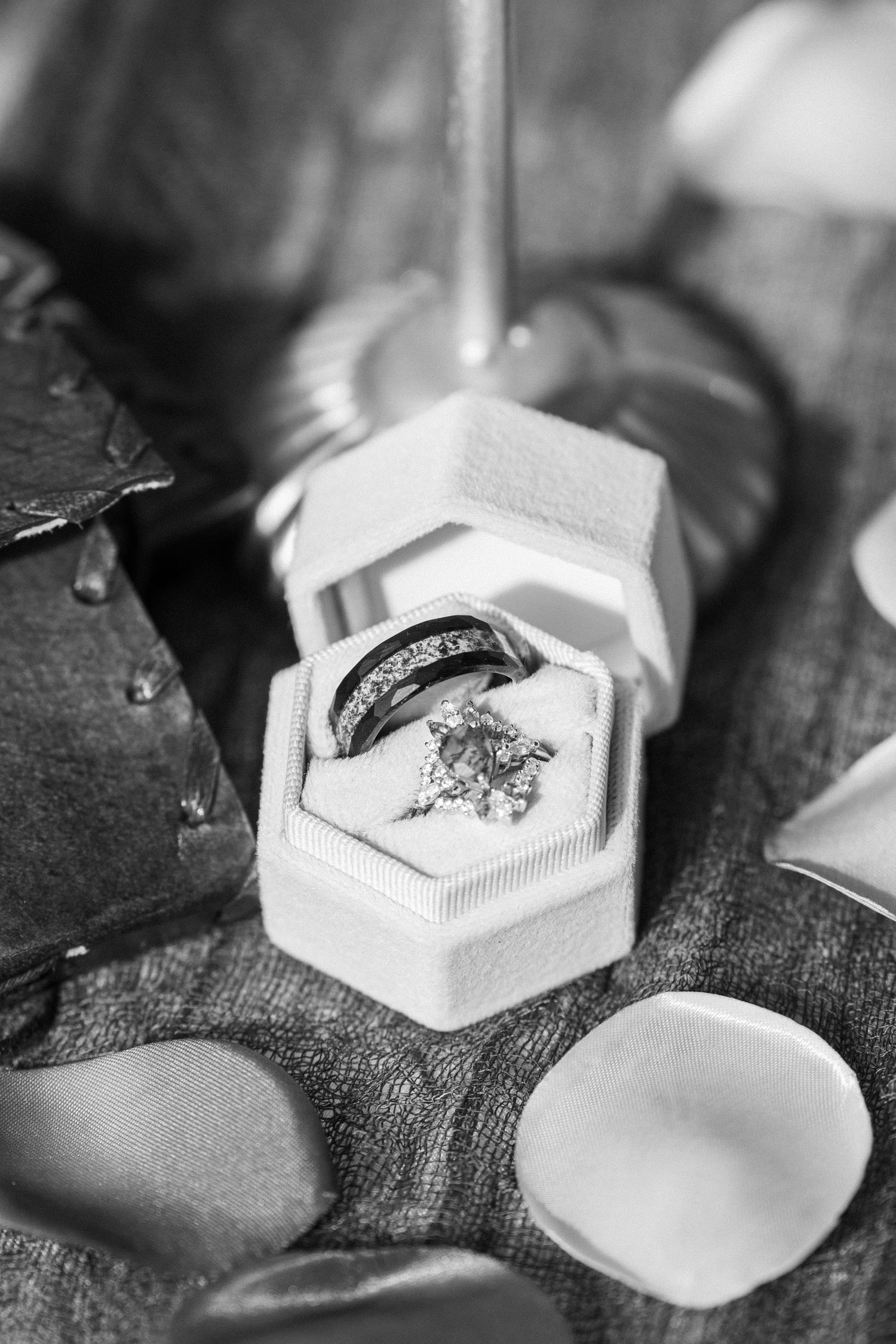 Black and white macro shot of an engraved wedding ring in a hexagonal white box.