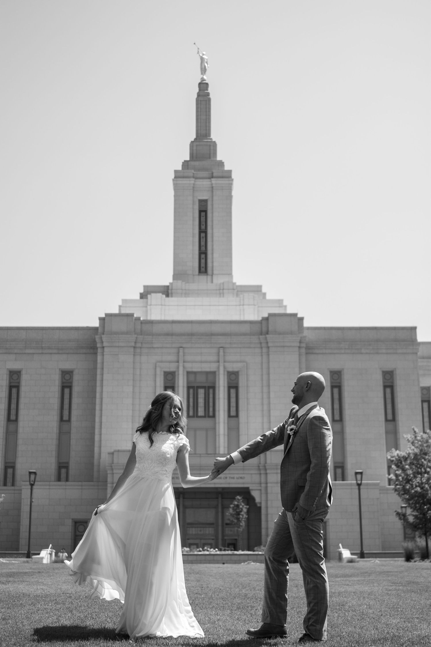 Bride and groom dance in front of Rexburg temple on wedding day.