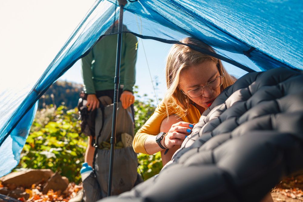 Blue tent canopy provides shelter at a scenic outdoor camping spot on a sunny day.