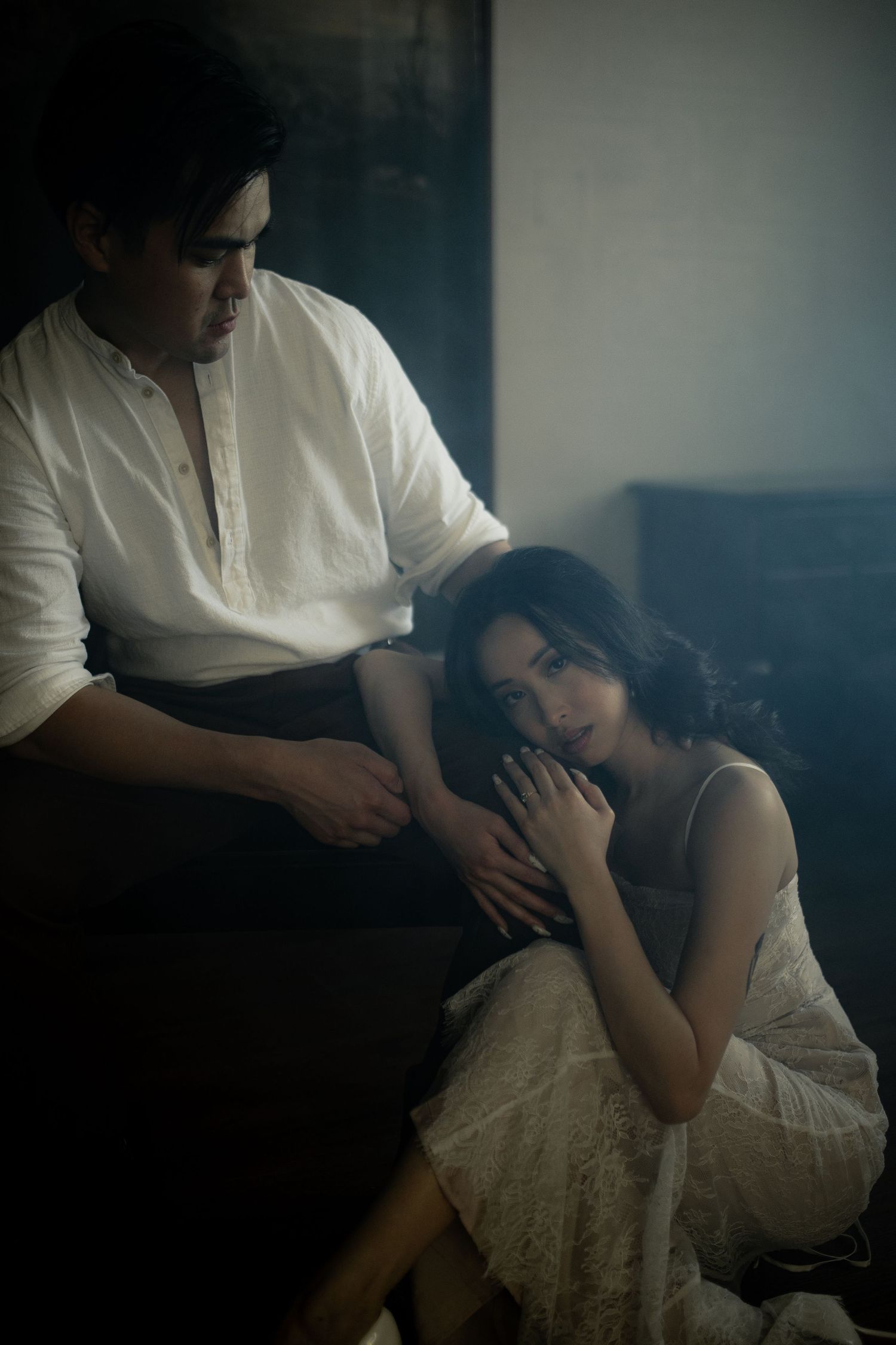 Intimate scene on a couch with dramatic lighting and white dress details.