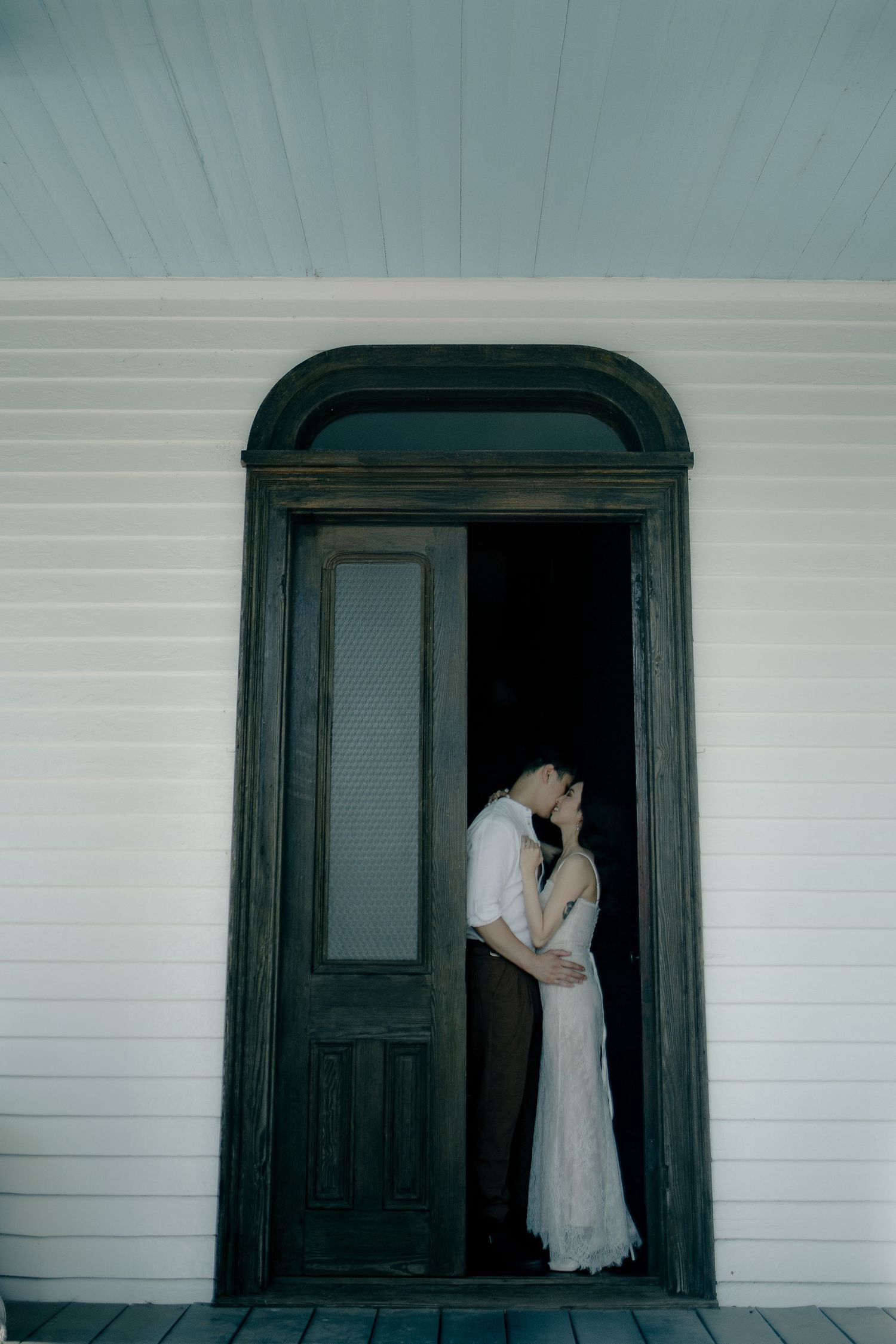 Atmospheric sequence at a doorway of a white house with dark trim showing intimate moments.